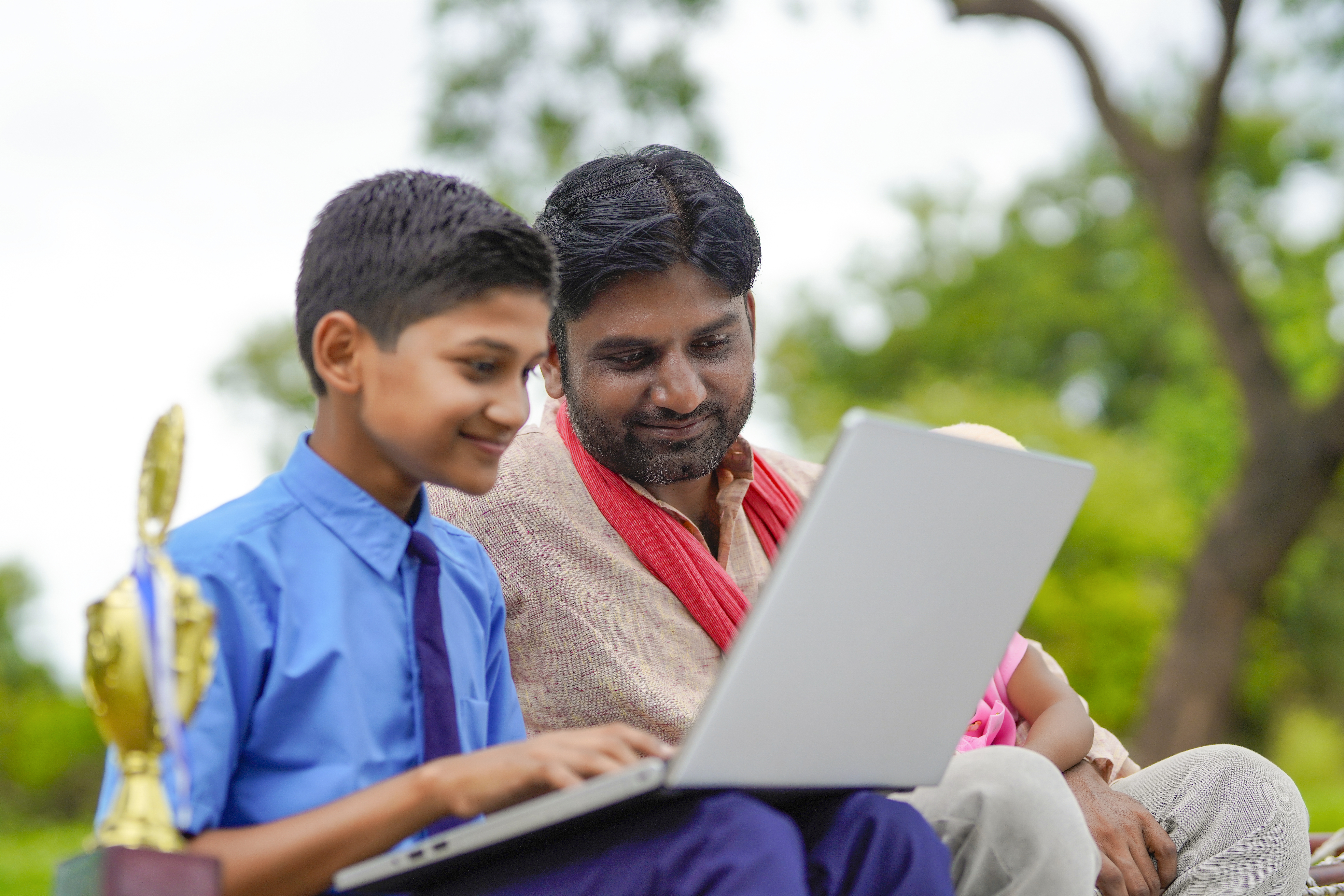 Education concept :cute indian school boy using laptop and giving some information to his father.